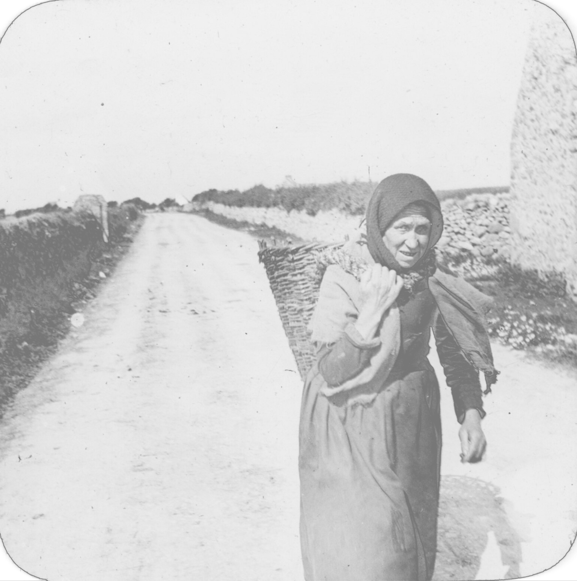 Frau mit Kopftuch und Korb auf dem Rücken.